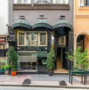 Un bâtiment sur lequel on peut lire l’inscription « HÔTEL LAVANTA » et qui est doté d’un auvent noir. Des plantes en pot sont disposées devant l’entrée.