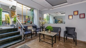 A modern living room with a sofa, chairs, a coffee table, and a staircase leading to an outdoor area with plants and a view of a restaurant. - Lavanta Hotel (Istanbul)