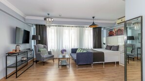 A modern living room with a sofa, armchair, TV, and a large mirror. - Lavanta Hotel (Istanbul)