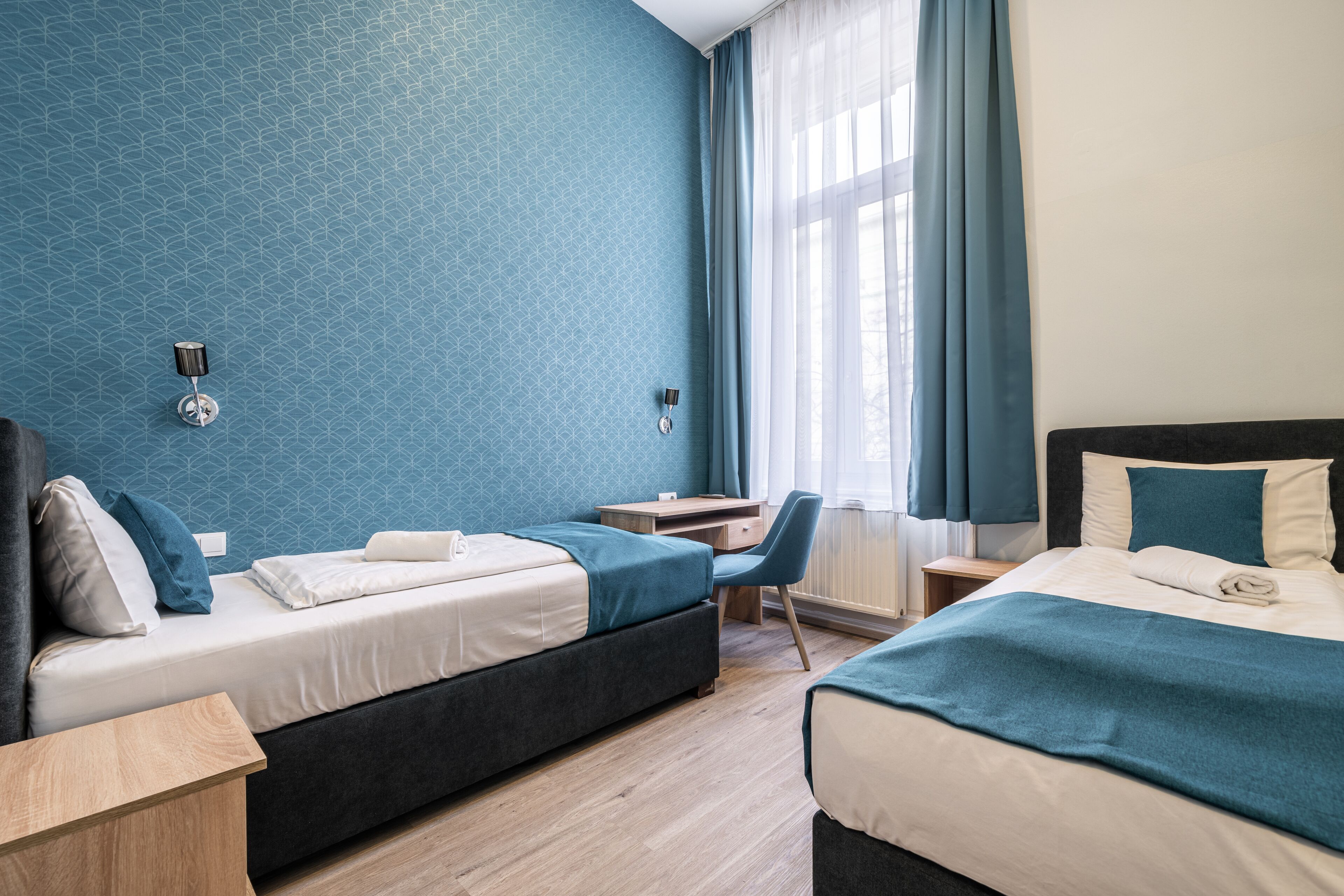 A hotel room with two beds, a desk, and a chair.