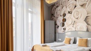 A hotel room with a large bed, a wardrobe, a mirror, and a wall with a floral pattern. - Full Moon Budapest (Budapest)