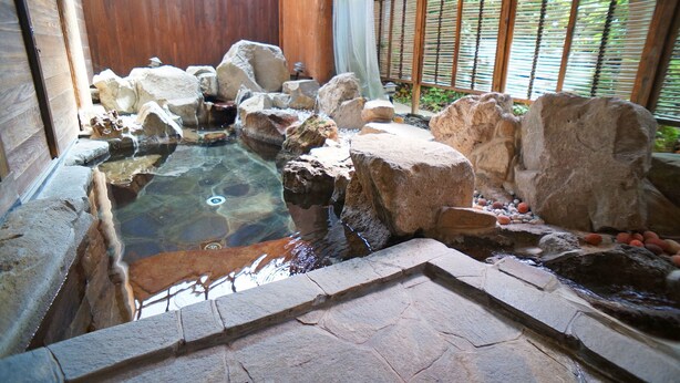 A hot spring area with a stone pathway, wooden deck, and a wooden fence. - Hot Spring Inn Banya (Yufu)