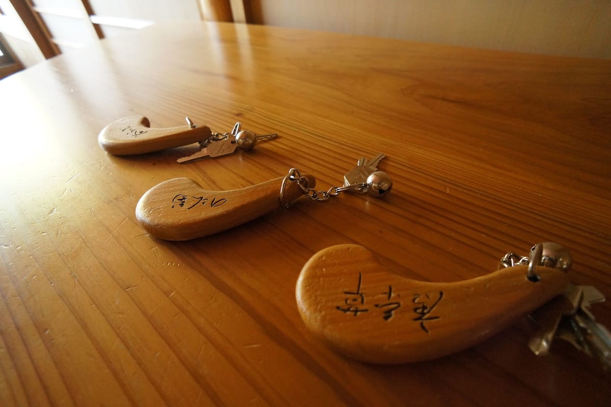 A wooden table with three keychains on it.