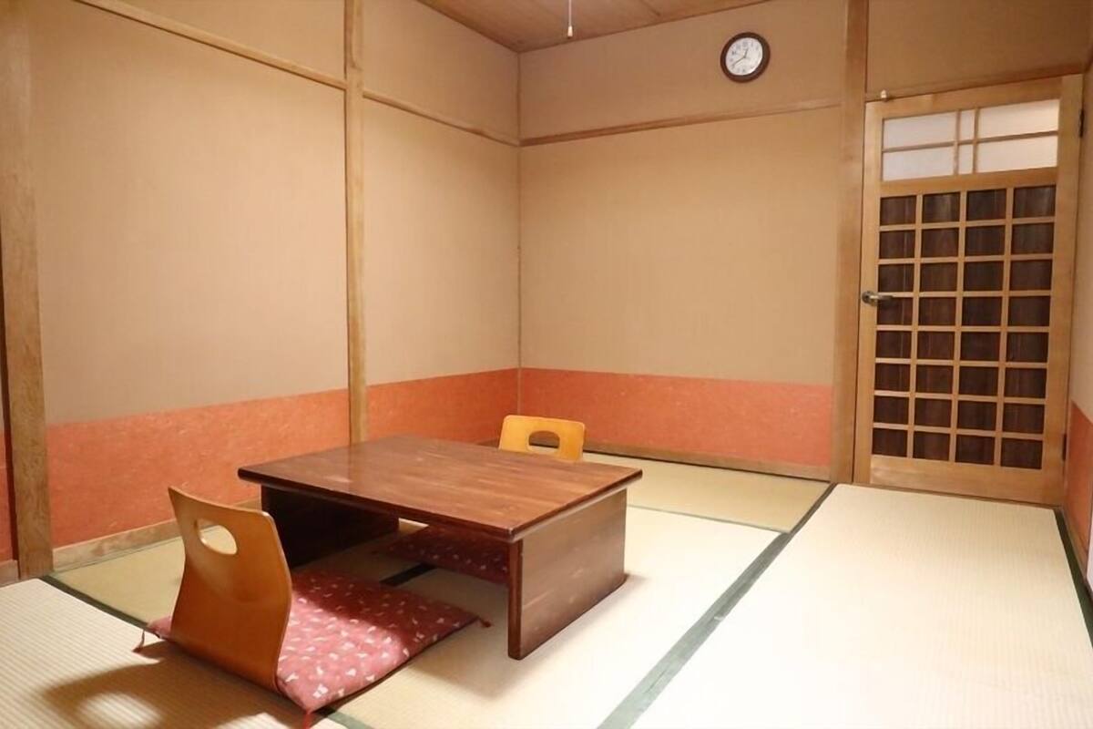 A traditional Japanese room with tatami flooring, a wooden table, and a shoji screen door.