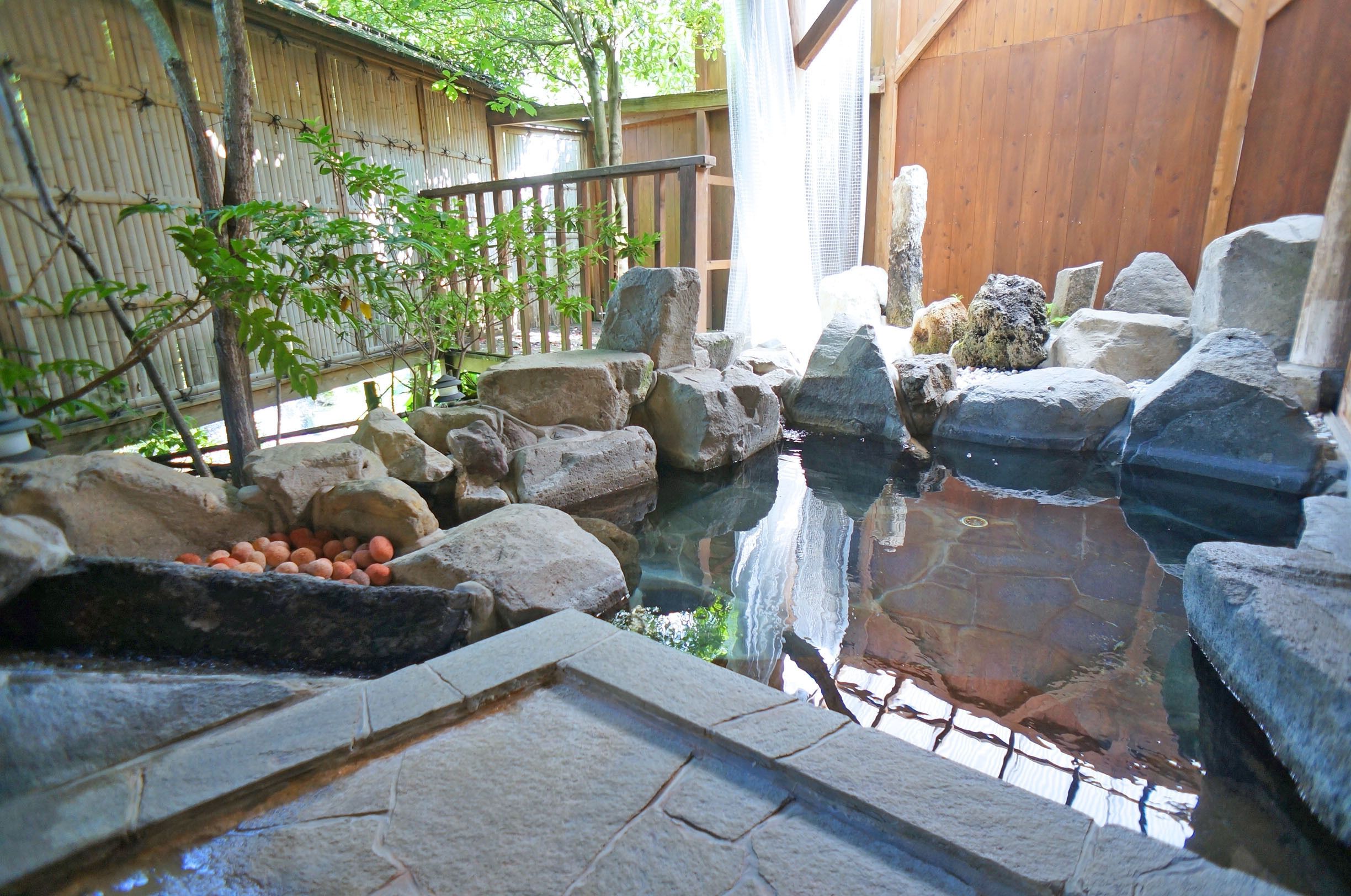 A traditional Japanese garden with a koi pond, stone lanterns, and a wooden fence.