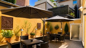 An outdoor patio with a table and chairs, potted plants, and a large umbrella. - Hotel Select (Moenchengladbach)