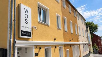 Un edificio de hotel con un letrero que dice 'WOS HOTEL EINGANG' y puertas numeradas.