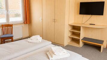 Quarto de hotel com duas camas, televisão, escrivaninha e uma cadeira.