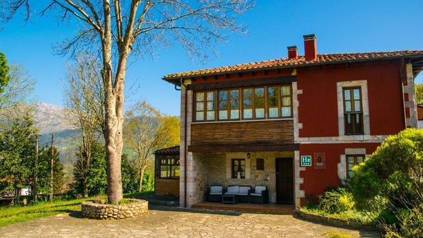 Un bâtiment à deux étages, doté d’une façade en pierre, d’un étage supérieur en bois et d’une entrée couverte avec des places assises à l’extérieur.