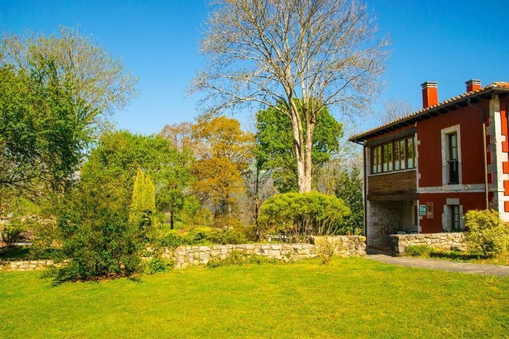 A red building with a stone wall and a grassy lawn.