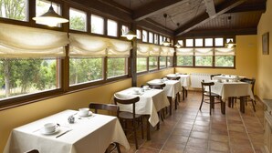 Un espace repas avec plusieurs tables préparées pour le service du thé, de grandes fenêtres avec des rideaux et un plafond en bois.