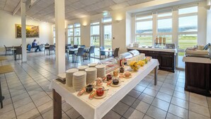 Een eetruimte met een buffet, stoelen en uitzicht op de omgeving.