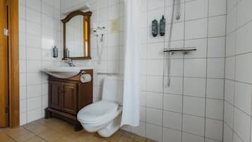 Ein Badezimmer mit weißem Waschbecken, Holzschrank, Toilette und Duschbereich mit Vorhang.