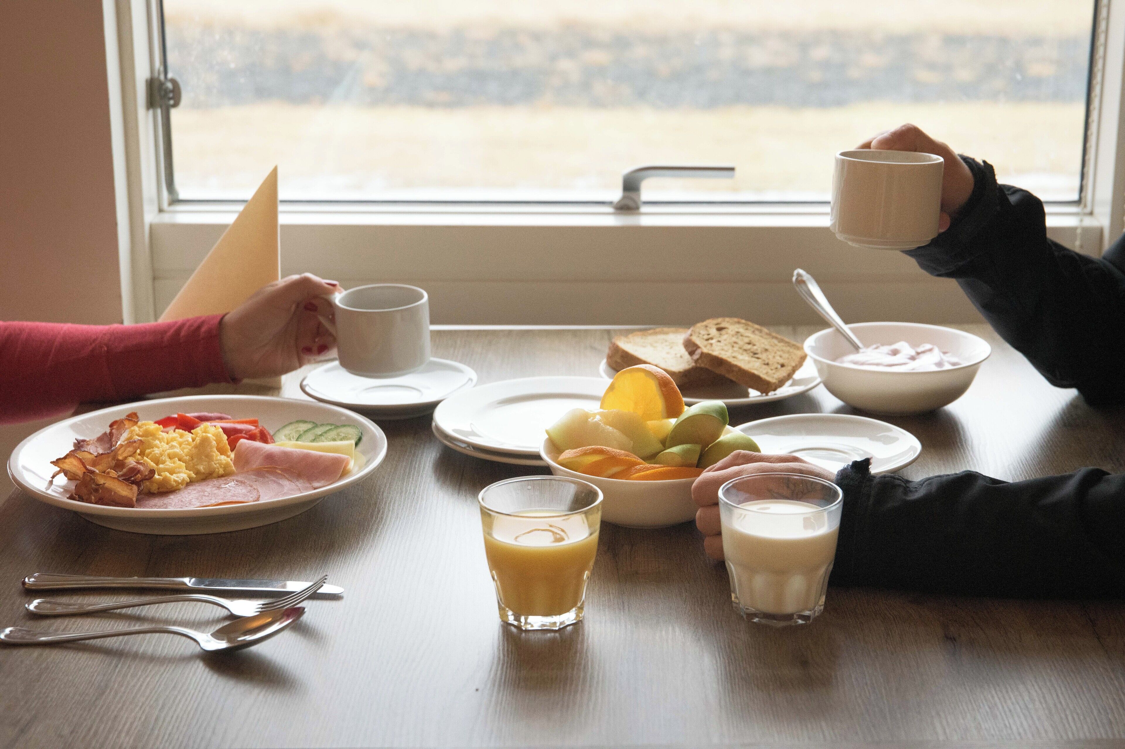A breakfast table with plates of food, glasses of juice, and a cup of coffee.