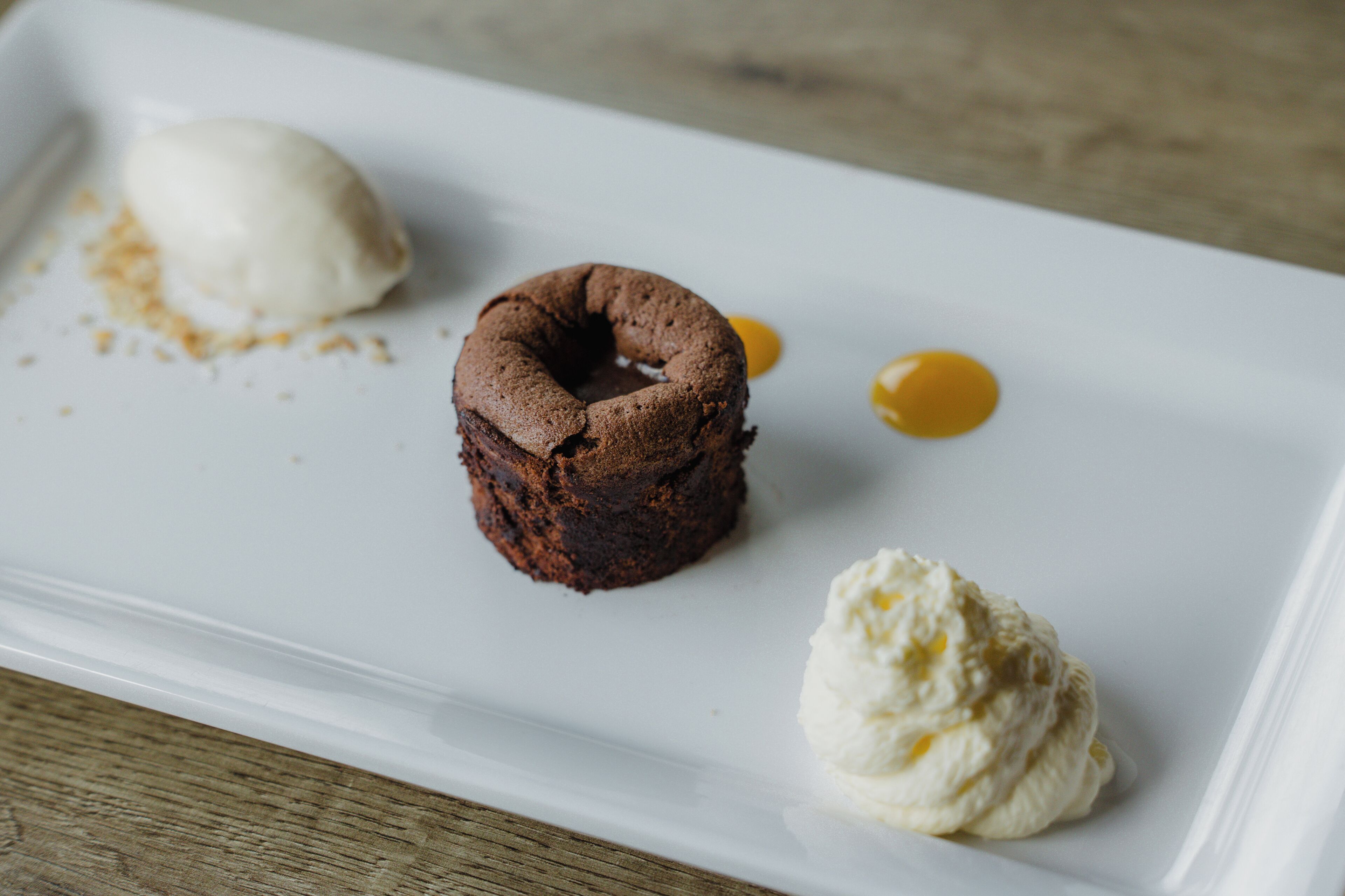 A dessert plate with a chocolate cake, a scoop of vanilla ice cream, and a dollop of whipped cream.