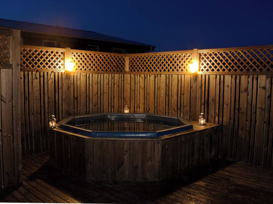 A wooden hot tub with two lanterns on either side, surrounded by a wooden fence.
