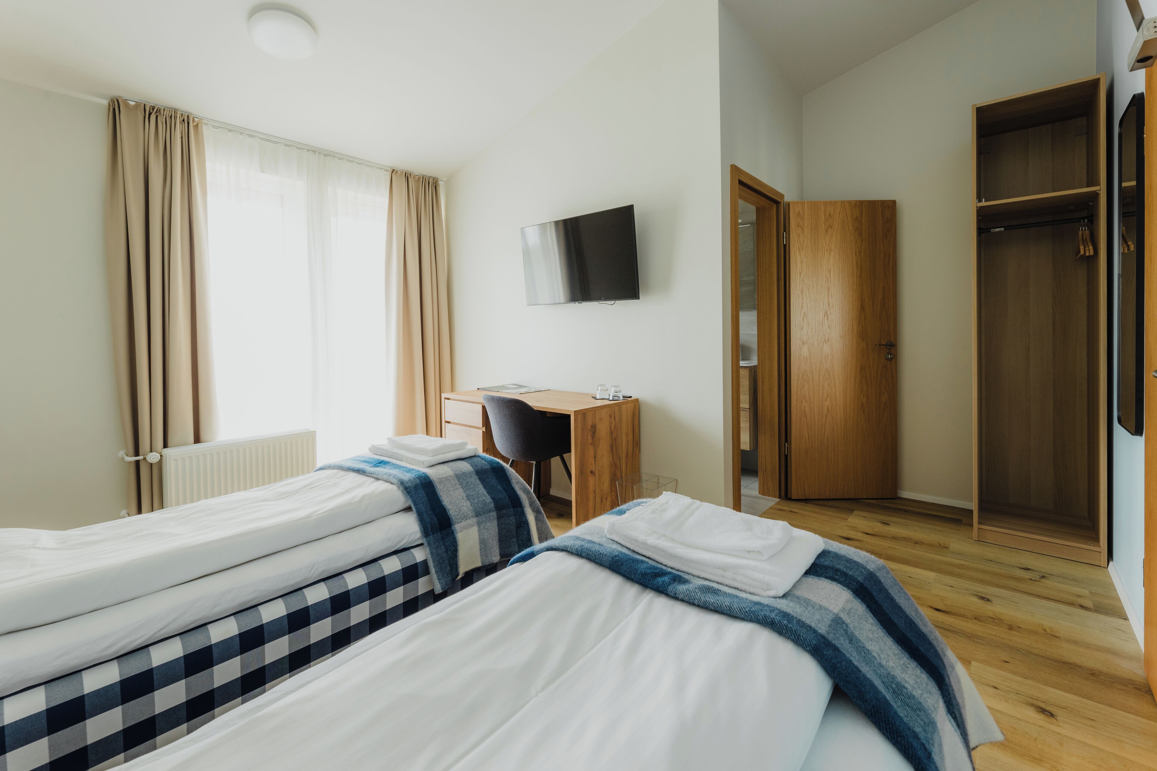 Une chambre d’hôtel avec deux lits, un bureau, une télévision et une armoire.