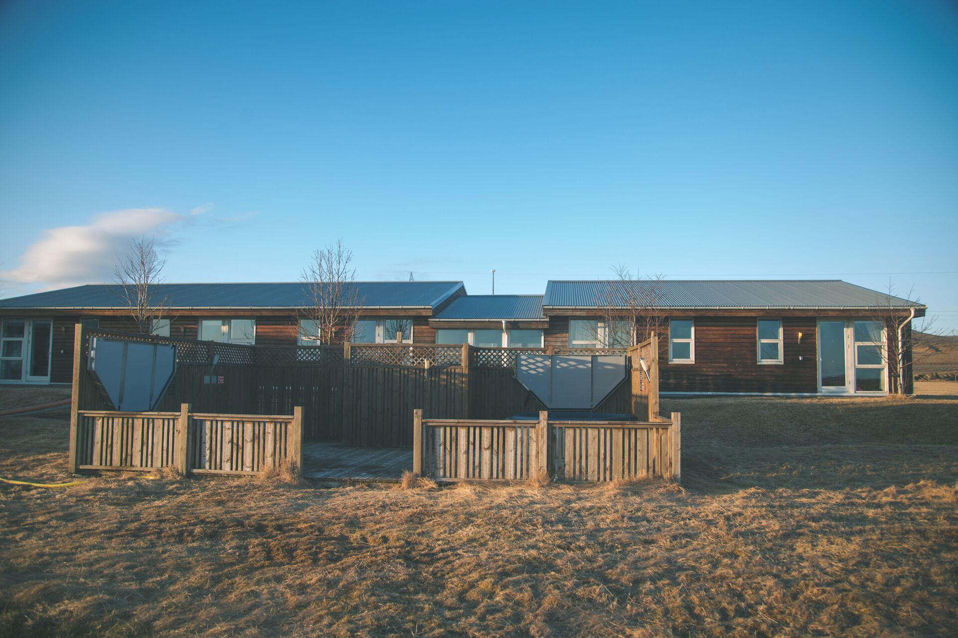 Une rangée de maisons modernes en bois, dotées de grandes fenêtres et d’une cour clôturée.