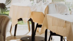 A dining area with tables set for two, large windows, and hanging pendant lights. - Hotel Gschwangut (Lana)