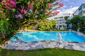 A swimming pool surrounded by stone tiles, with a statue in the center. - Hotel Gschwangut (Lana)