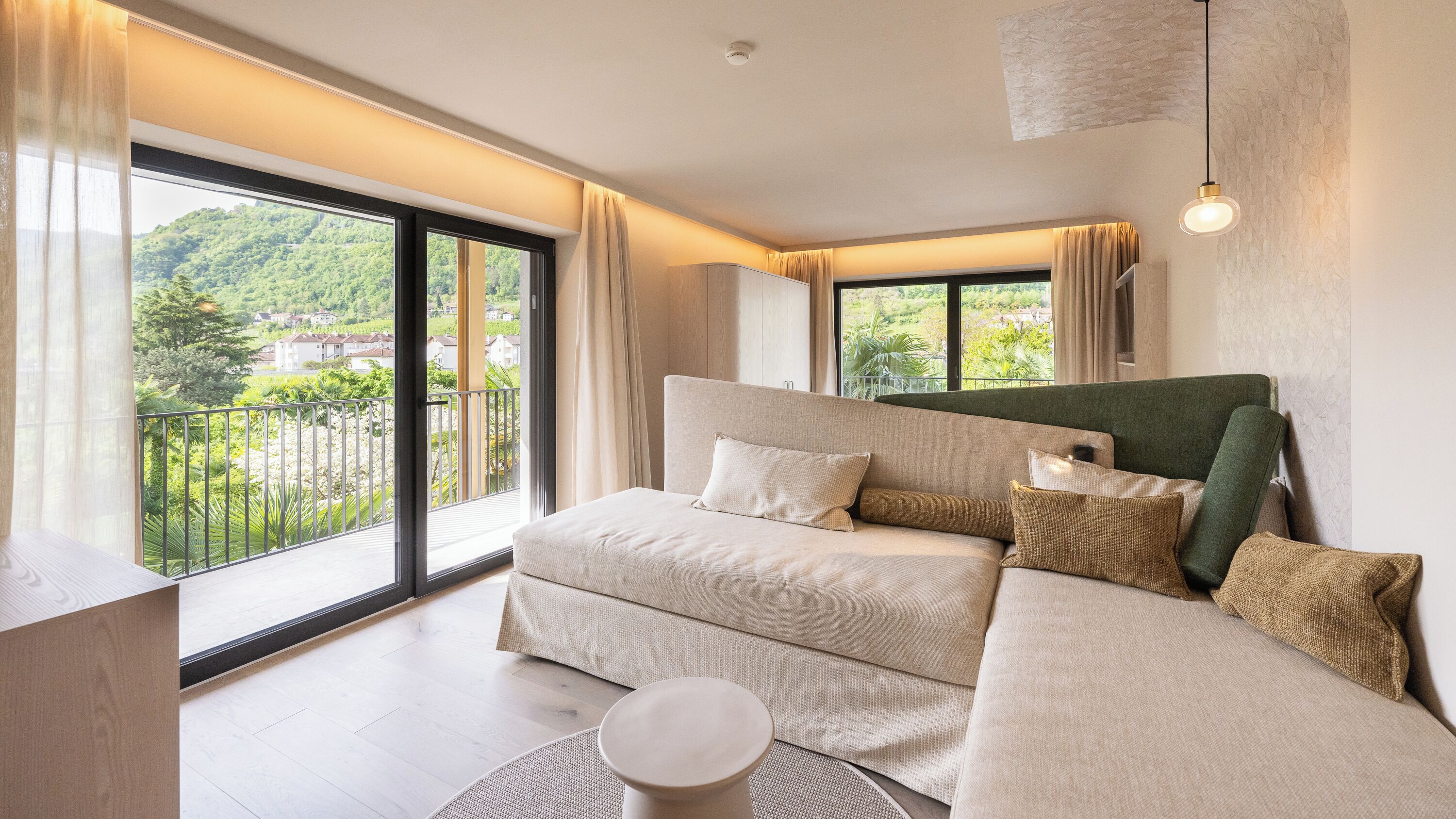 Una camera da letto moderna con un letto grande, un tavolino e un balcone con vista sul verde.