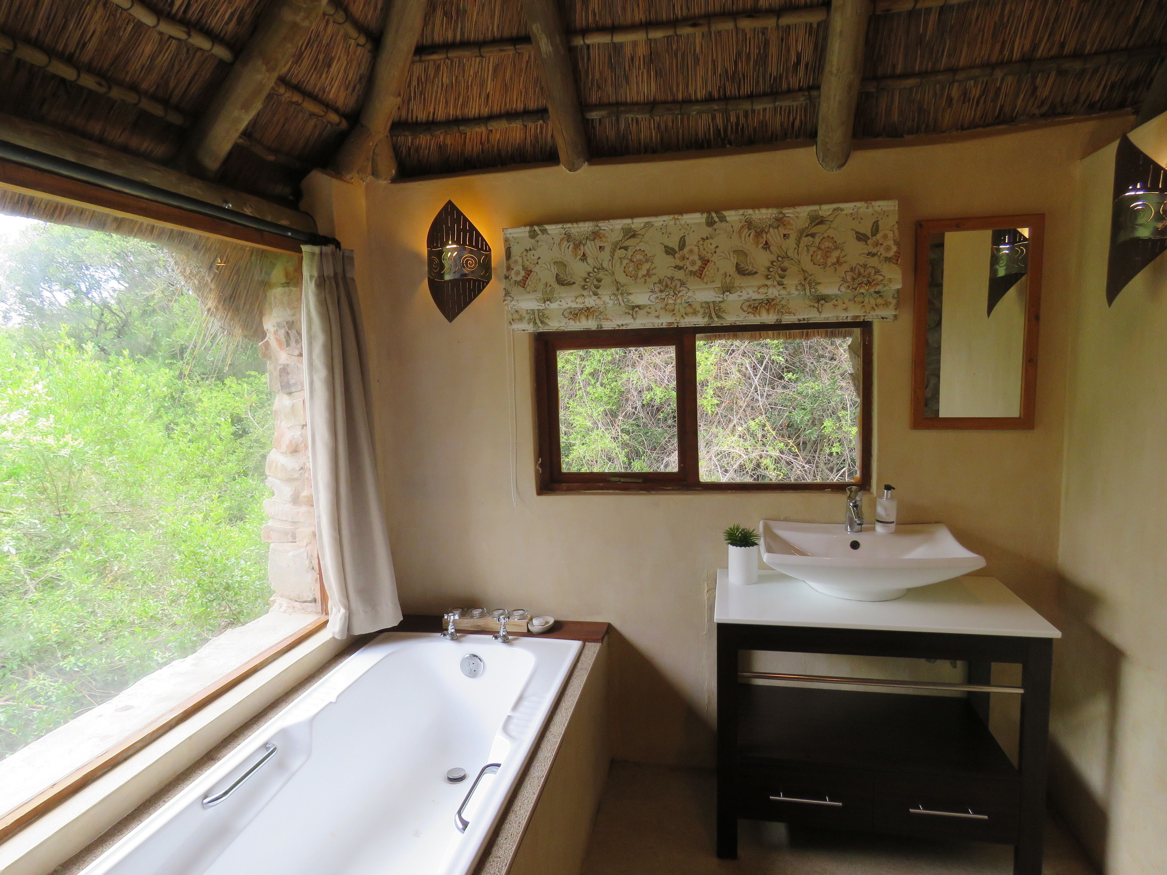 Un baño con bañera, lavabo y ventana con vistas a la vegetación.