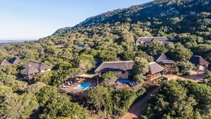 Un resort con villas de techo de paja, piscina y abundante vegetación.