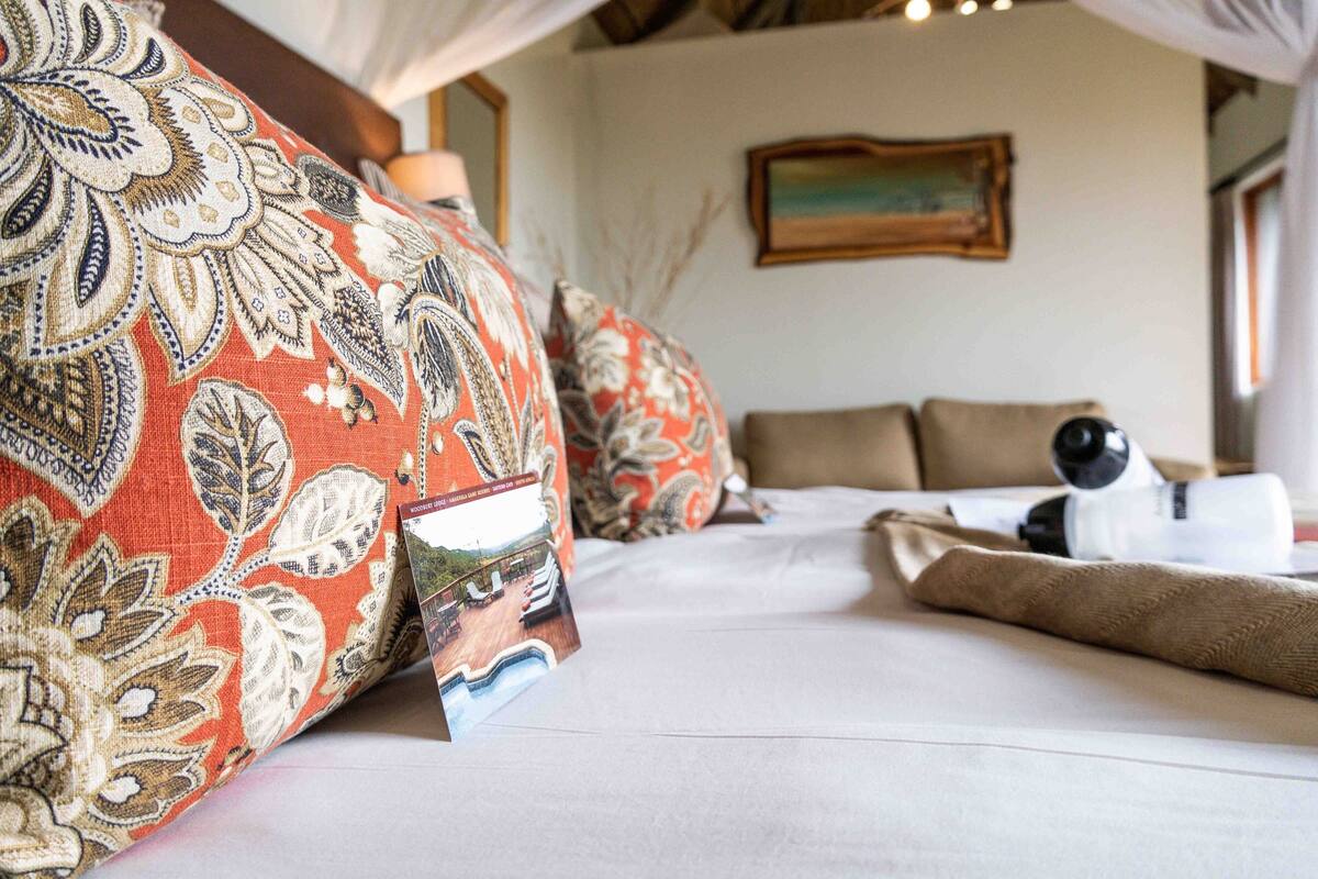 Una cama bien hecha con almohadas estampadas y un cuadro en el lateral.