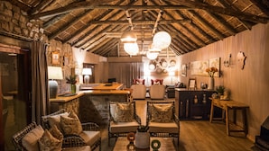 Una habitación acogedora con mobiliario de mimbre, techo de madera y pared de piedra.