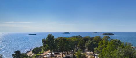 A coastal RV park with multiple RVs parked among trees, overlooking the sea and small islands.
