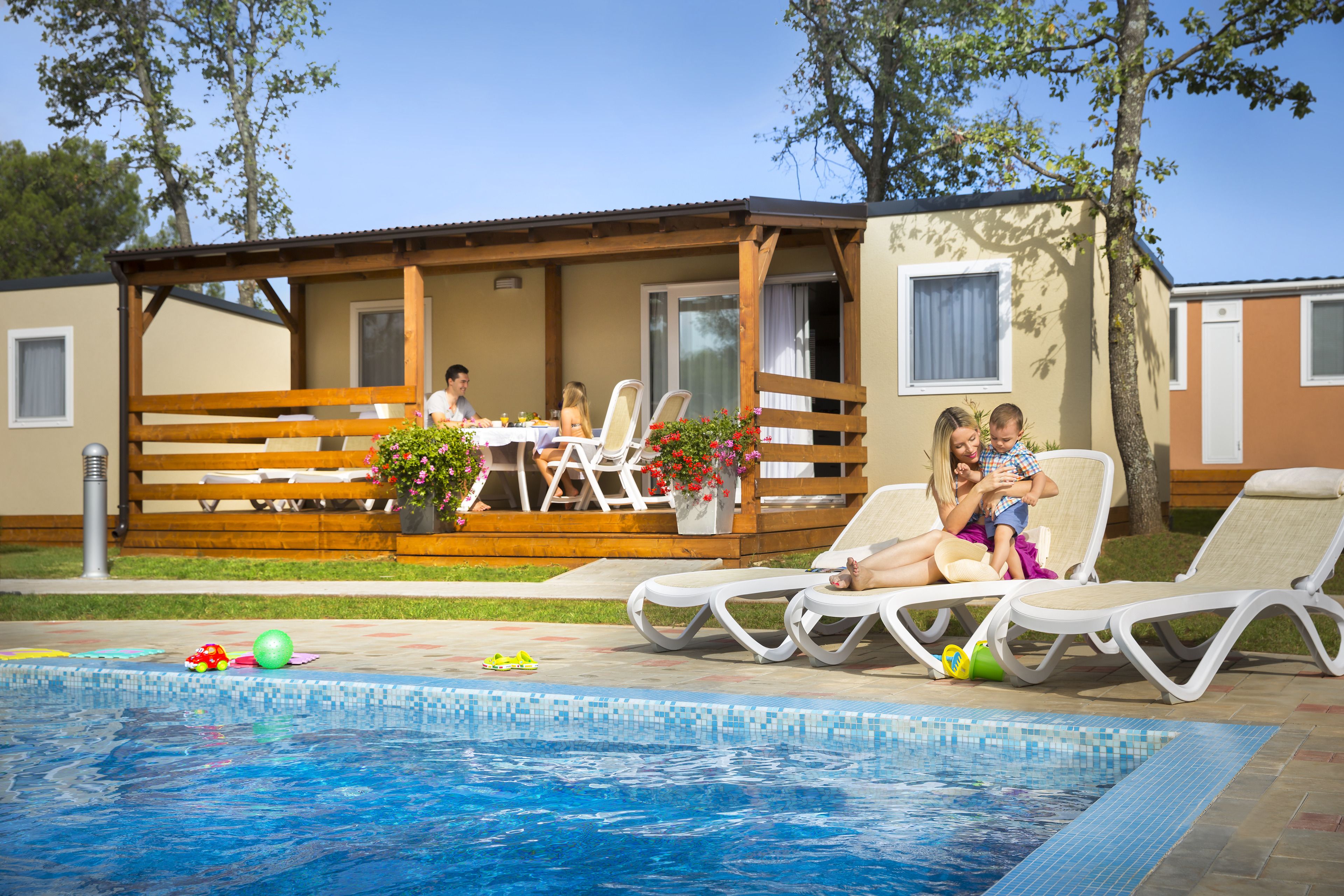 A poolside area with lounge chairs, a dining table, and a covered patio.