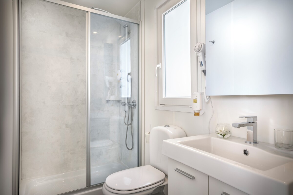A modern bathroom with a glass shower enclosure, a white toilet, and a sink with a mirror above it.