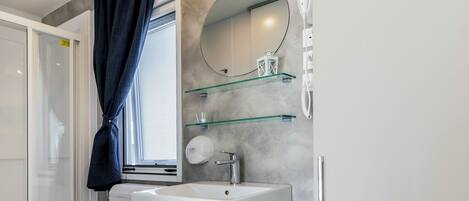 Un baño moderno con inodoro, lavamanos y ducha.