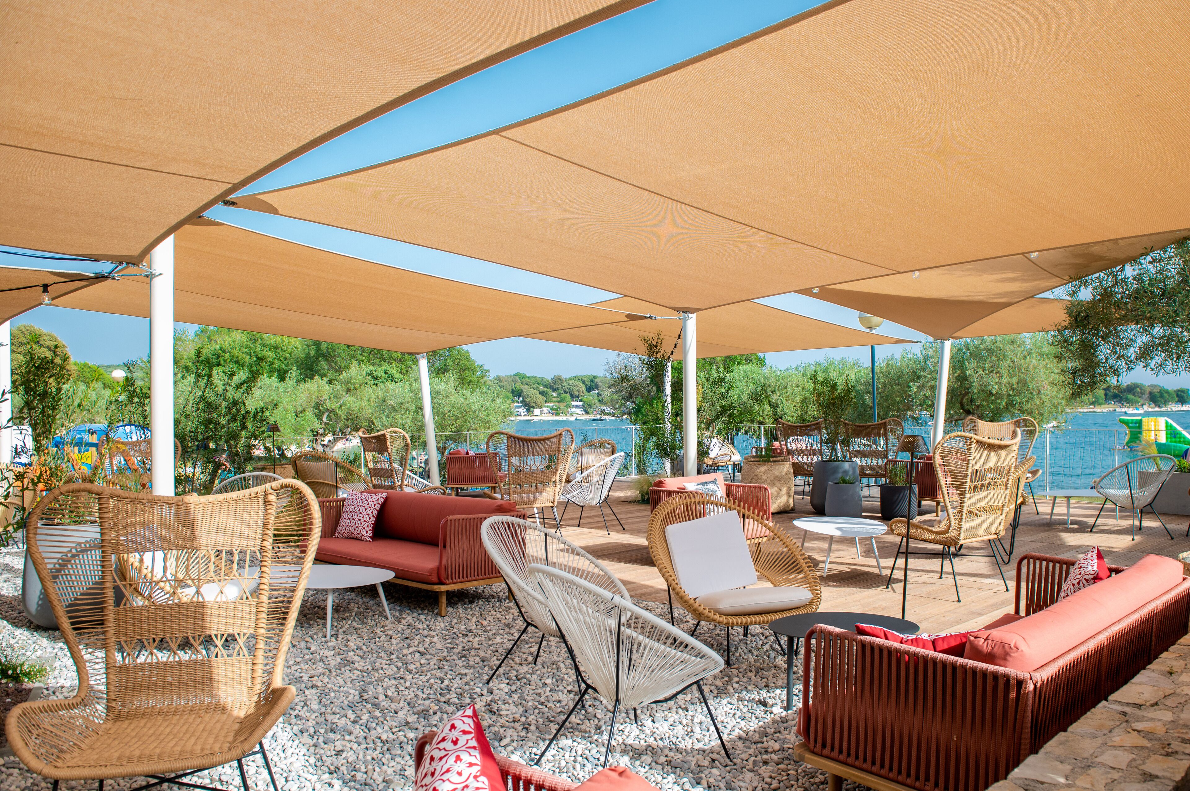 Een terras met rieten meubels en uitzicht op een waterpartij.