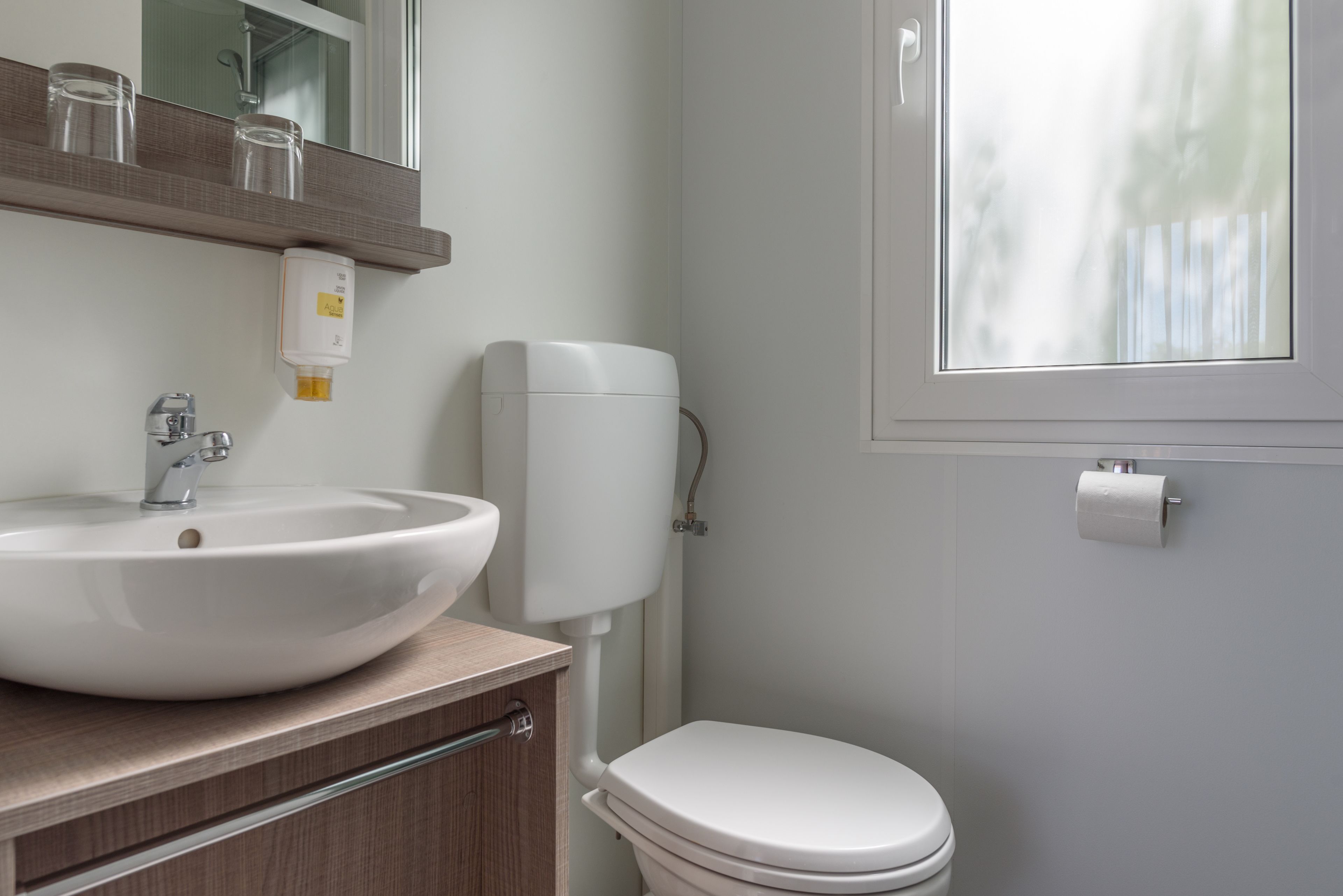 Une salle de bain avec un lavabo blanc, un miroir et des toilettes.