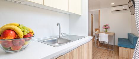 Een moderne keuken met een fruitschaal, een gootsteen en een zithoek met een blauwe bank en een kleine tafel.