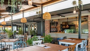 An indoor dining area with wooden tables and chairs, hanging wicker lamps, and a brick column. - Maistra Camping Polari Mobile homes   (Rovinj)