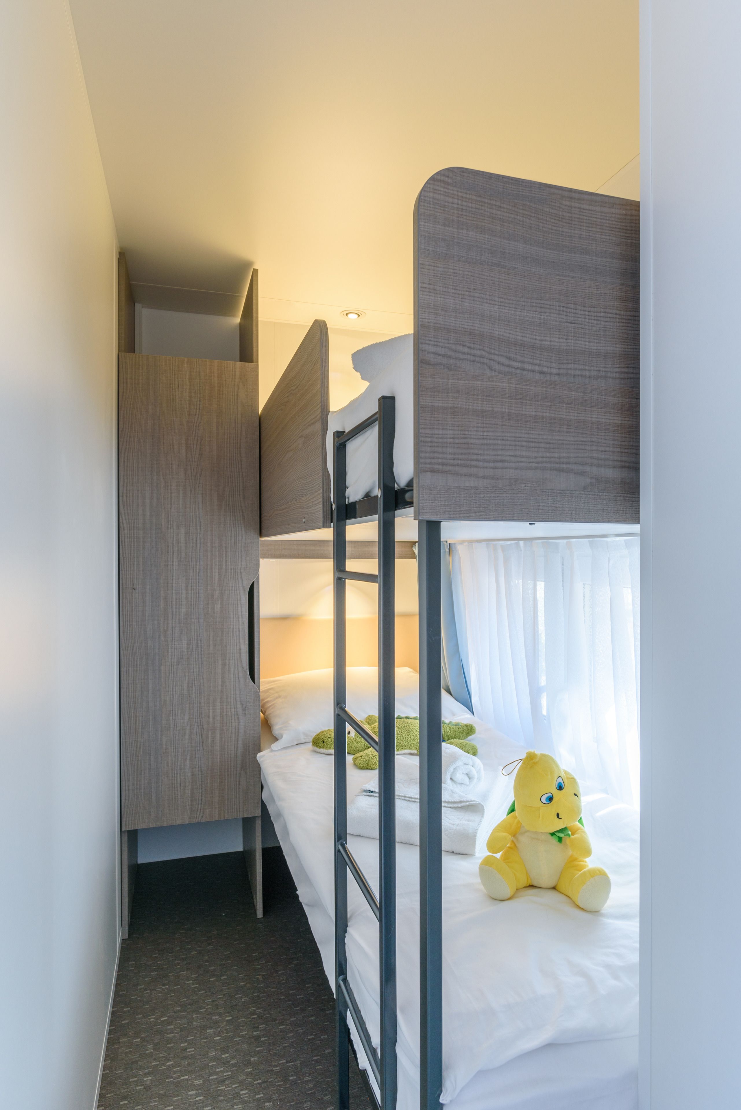 Ein Etagenbett mit einem Holzschrank und einem Stofftier im unteren Bett.