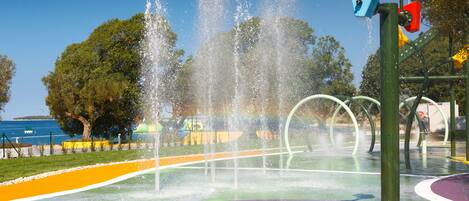 A water play area with multiple fountains and a colorful ground surface.