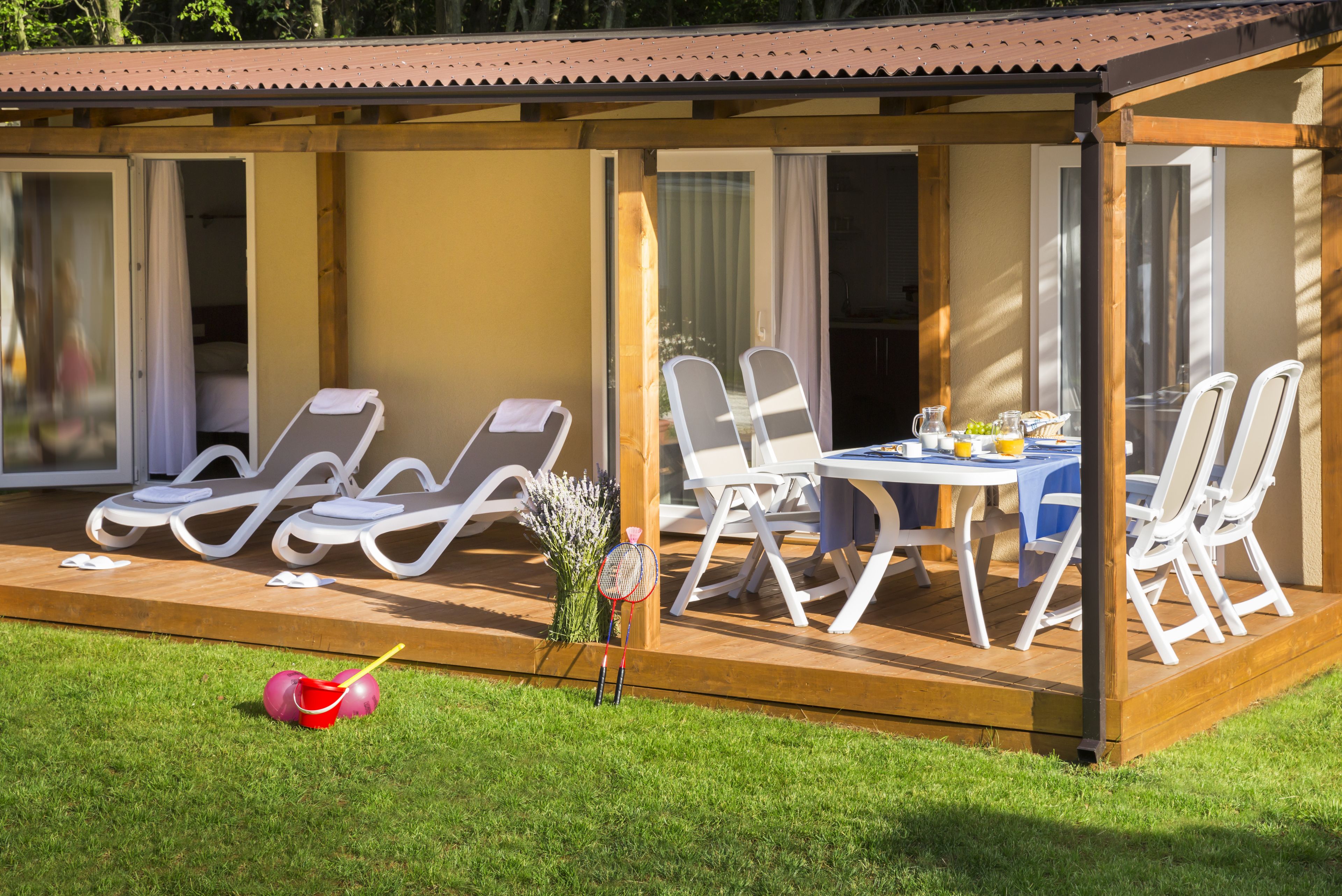 A covered outdoor seating area with lounge chairs and a table set for dining.