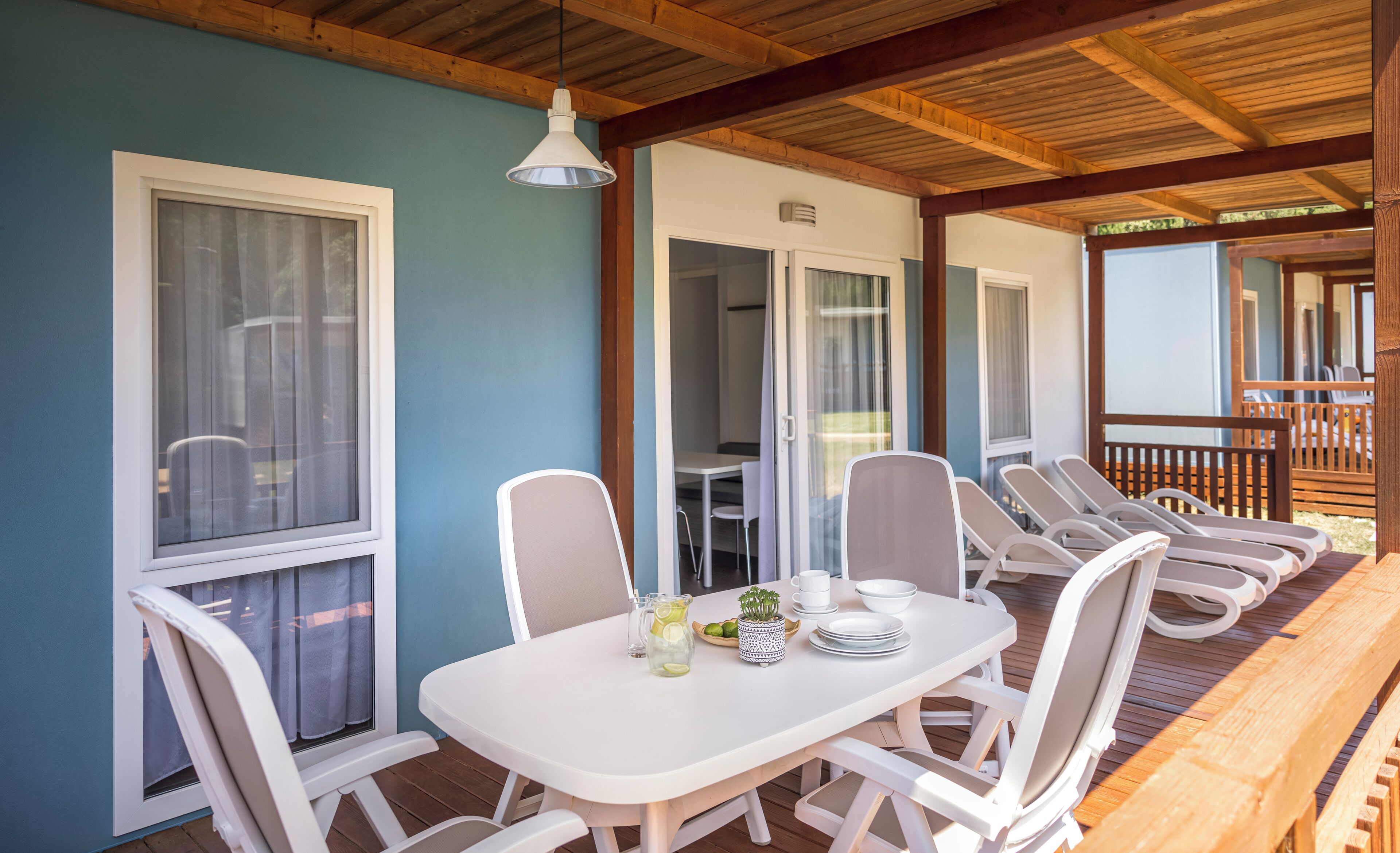A covered outdoor seating area with a table and chairs, a ceiling fan, and a view of the deck.