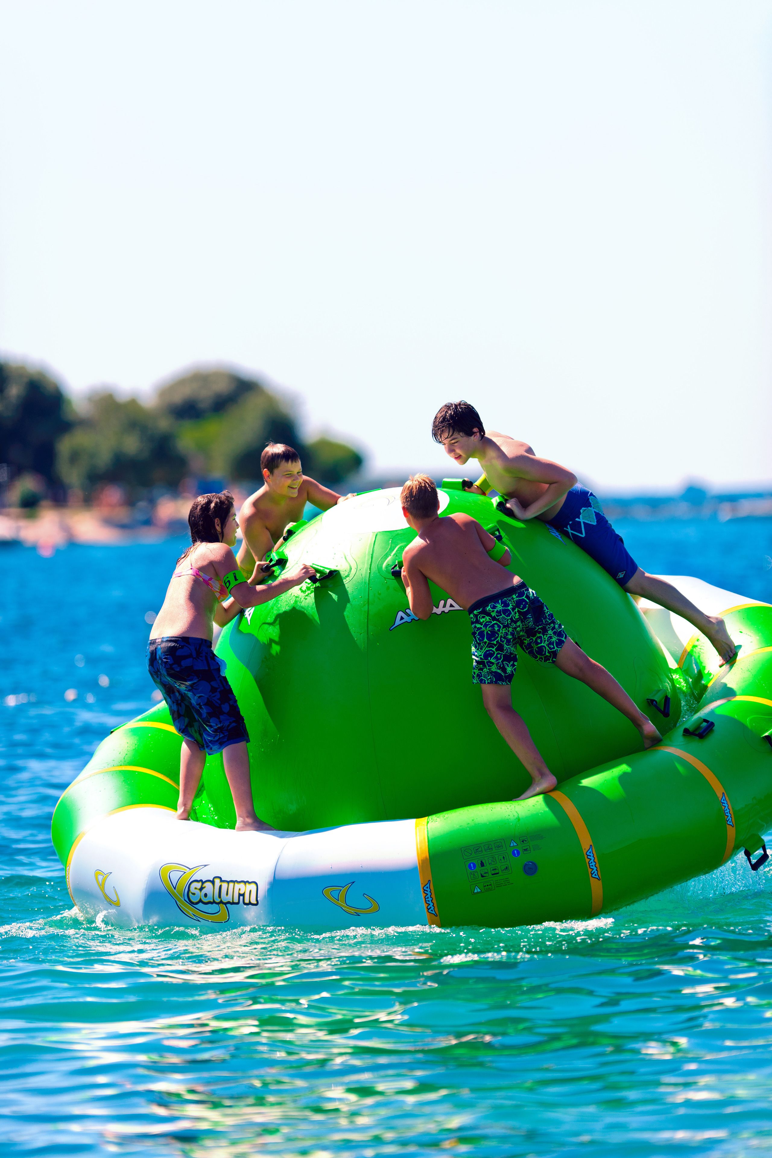 A group of people on a green inflatable raft in the water.