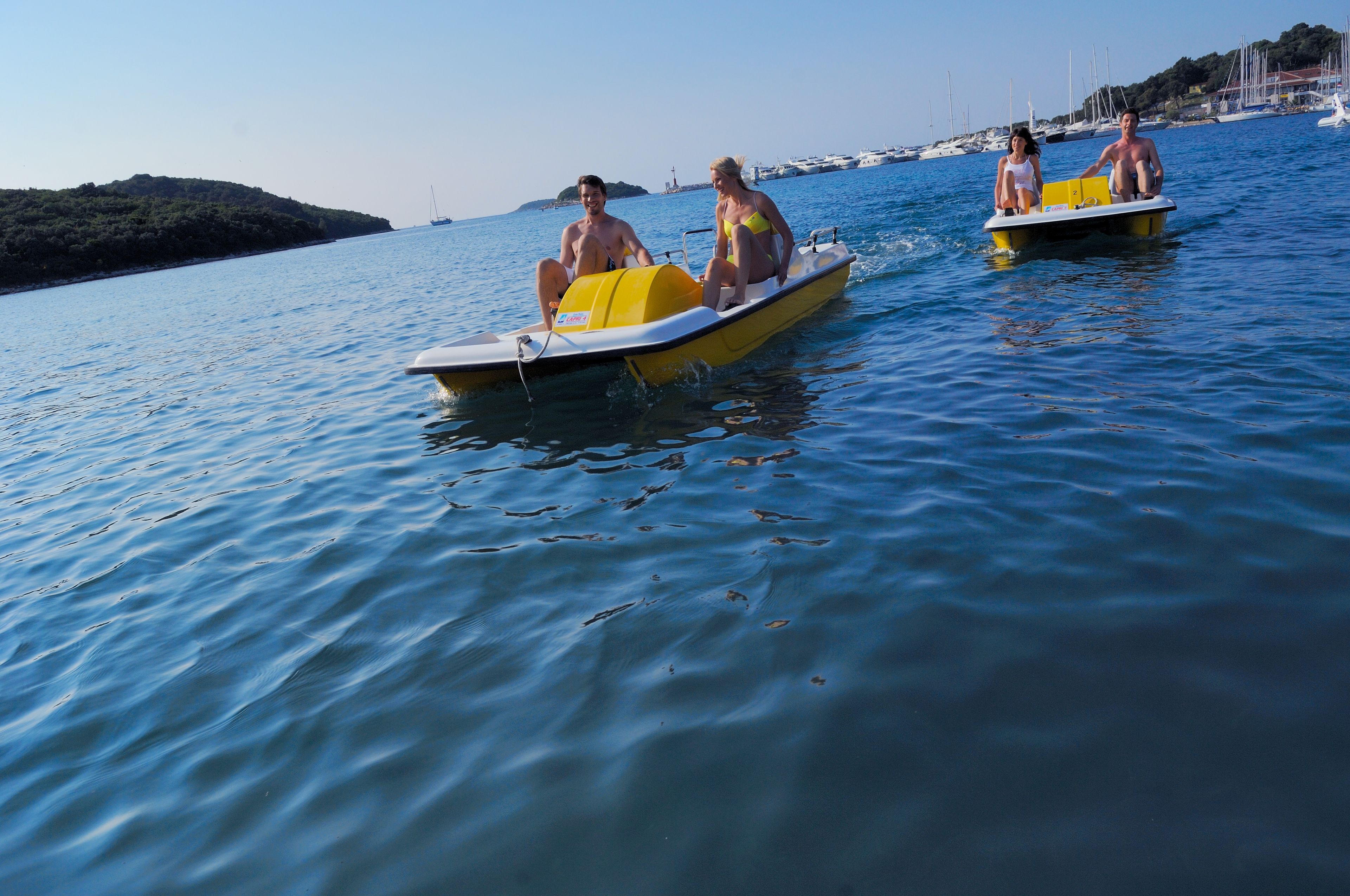 Two people on a yellow boat in calm water.