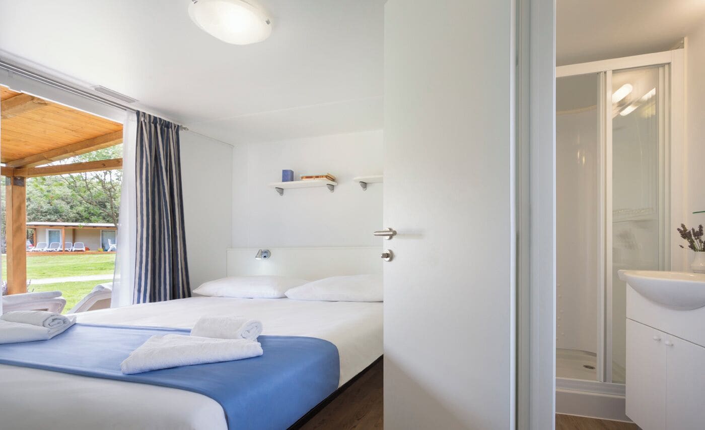 A modern hotel room with a bed, a shower, and a view of the outdoors.