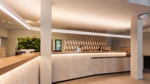 A modern reception desk with a wooden counter and a textured wall behind. - Maistra Camping Polari Mobile homes   (Rovinj)