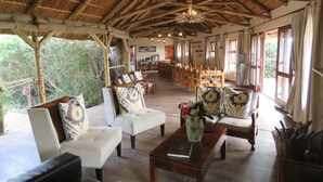 A spacious lodge with a thatched roof, wooden furniture, and a dining area. - Woodbury Tented Camp - Amakhala Game Reserve (Sidbury)