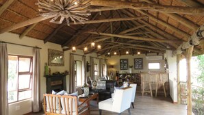 A spacious room with a high wooden ceiling, a fireplace, a dining area, and a bar. - Woodbury Tented Camp - Amakhala Game Reserve (Sidbury)