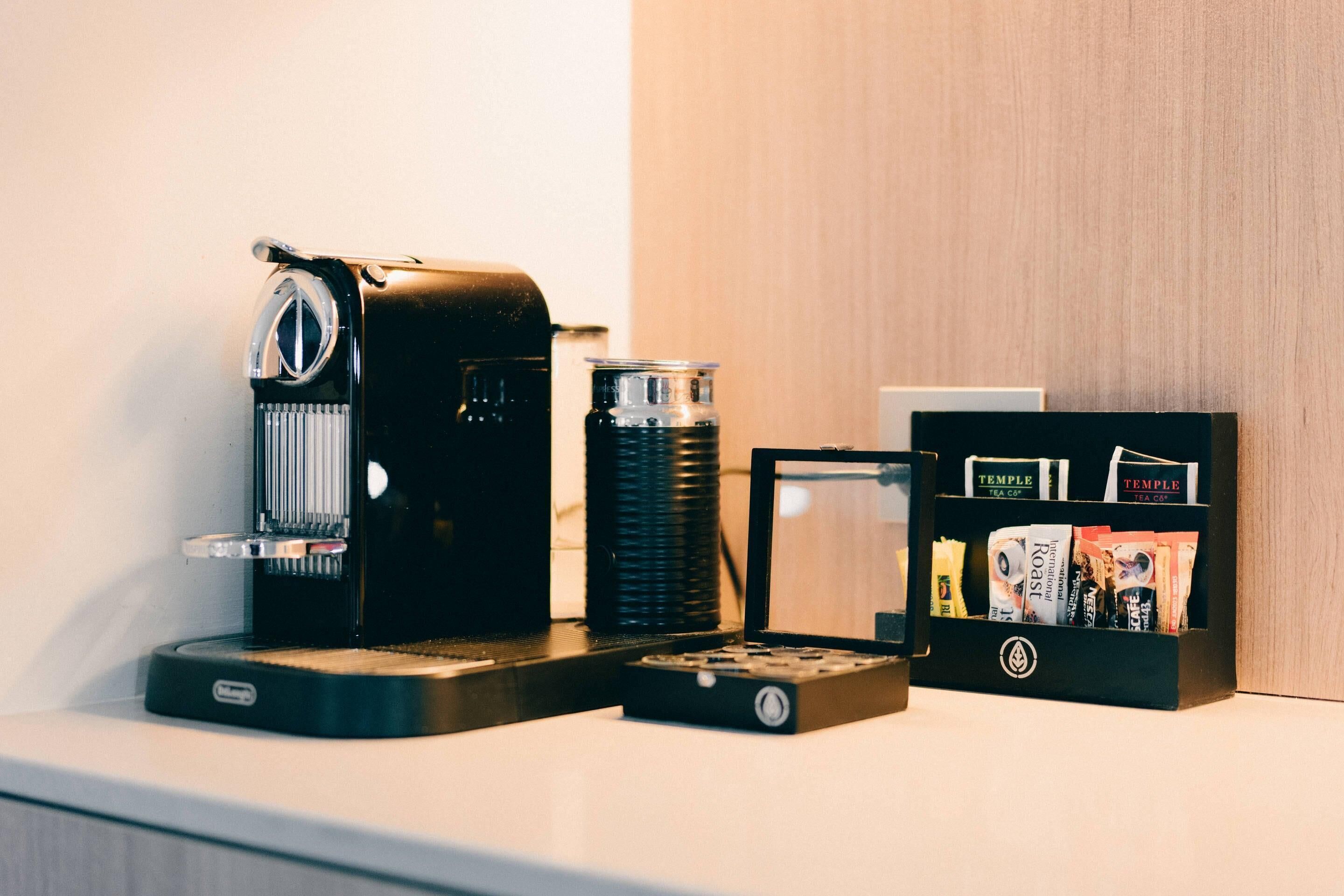 A coffee machine, a thermos, and a tea bag holder on a counter.