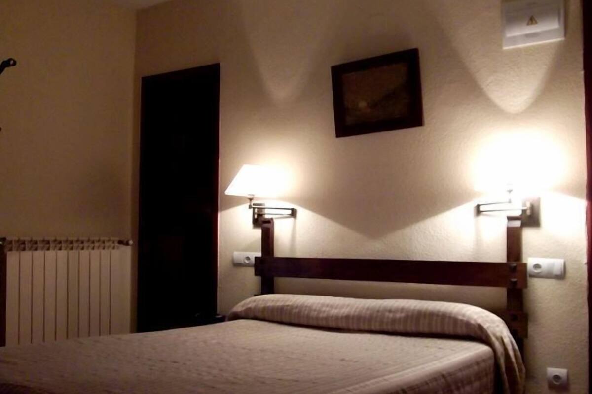 Ein Hotelzimmer mit einem Bett, zwei Nachttischlampen, einer Heizung und einer Tür.