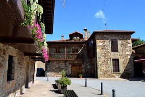 Un edificio de piedra con un balcón de madera, una puerta de madera y un patio empedrado.